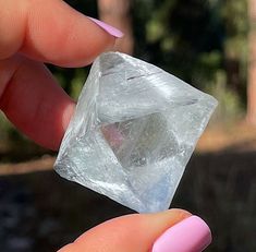 a person holding a piece of ice with pink nails on their fingers and fingernails