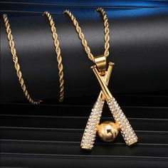 two gold necklaces on top of a black surface with a ball and chain attached to it