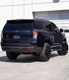 a large black truck parked in front of a garage