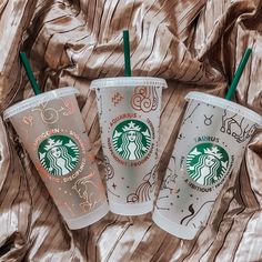 three starbucks coffee cups sitting on top of a bed