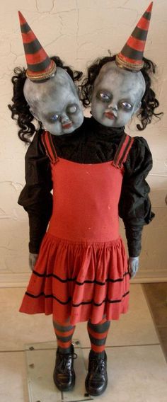 two creepy dolls dressed in red and black are standing next to each other on a mirror