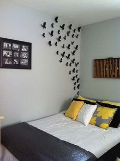 a bed with black and yellow pillows in a bedroom next to a framed photo on the wall