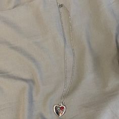 a silver heart necklace with two hearts attached to it on a white cloth covered bed