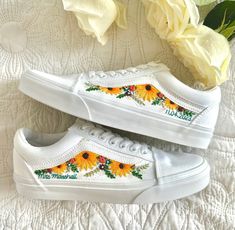 two white vans with sunflowers painted on them are sitting next to some flowers