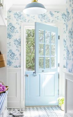 a blue door in a white room with floral wallpaper