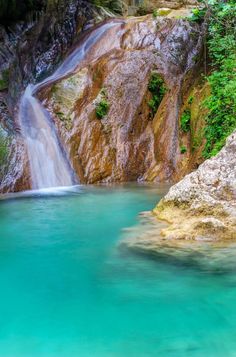 a small waterfall in the middle of a blue pool