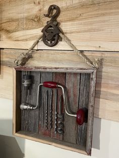 an old wooden box with tools hanging from it's side and some hooks attached to the wall