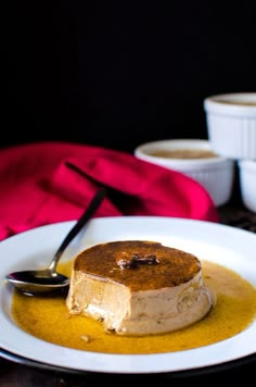 a piece of cake on a white plate with caramel sauce and two bowls in the background