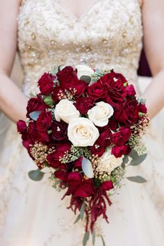 a bride holding a bouquet of red and white flowers