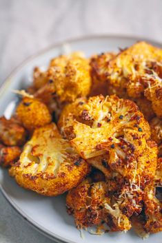 a white plate topped with fried cauliflower covered in grated parmesan cheese