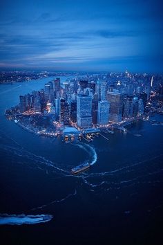 an aerial view of a city at night with boats in the water and lights on