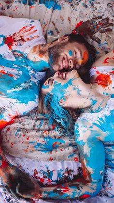 a woman laying on top of a bed covered in paint