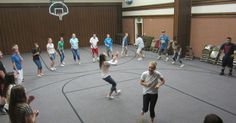 a group of people are playing basketball in an indoor court with chairs around the perimeter