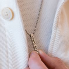 a person wearing a white shirt holding a silver necklace