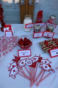 a table topped with lots of desserts and candies on top of a white table cloth