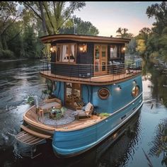 a blue houseboat floating on top of a river next to a lush green forest