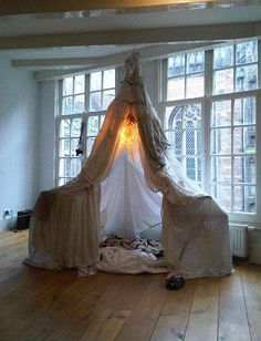 a white bed sitting on top of a hard wood floor next to two large windows