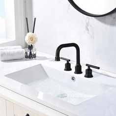 a white bathroom sink with black faucet and soap dispenser next to it