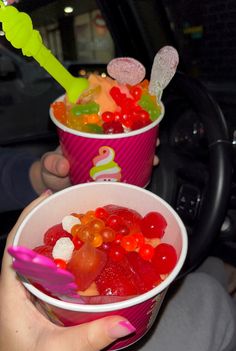 two cups filled with jelly beans and gummy bears on top of a car dash board