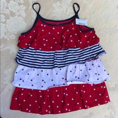 Top Is 20” Long From Top Of Shoulder (Top Of 6” X3/8” Spaghetti Straps). Chest Measurement: 29” Around Measured Underarms. Armholes: 16” Around; Scoop Neckline: 30” Around. Four 100% Cotton Knit 4.5” Wide Gathered Ruffles: Red With White Stars, White With Navy Stars And Navy & White Stripes On A Red Polyester Body. Machine Wash And Dry. Size L = 10/12. Cute Red Ruffled Top, Fun Red Tops For Playwear, Fun Red Top For Playwear, Playful Red Tops For Summer, Playful Red Summer Tops, Multicolor Ruffled Tops For Playwear, Red Tops For Spring Playtime, Red Cotton Tops For Playtime, Red Cotton Top For Playtime