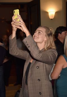 a woman taking a selfie with her cell phone in the air at an event