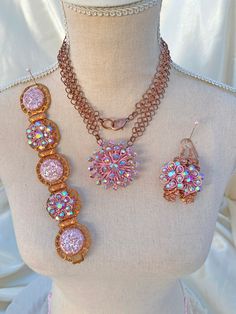 An outstanding vintage assemblage necklace, bracelet, and earrings set are done in pink and copper.  I simply adore the look of pink on copper!   This beautiful set starts with the lovely necklace with a well-made copper chain maille / chainmaille chain and a lobster claw clasp.  The pendant portion is an up-cycled vintage pink rhinestone starburst brooch.  Next is the vintage assemblage copper bracelet.  This is made with up cycled vintage earrings.  There are pink confetti earring components and pink rhinestone floral earring components that we incorporated into the solid copper band that has a fold-over clasp.   The earrings were made using another matching pair (yes, I found 2 different pairs of the same earrings of pink rhinestone floral earrings set on copper stampings.    This is a Vintage Rose Gold Jewelry For Evening, Rose Gold Vintage Jewelry For Evening, Vintage Rose Gold Jewelry With Matching Earrings, Handmade Pink Jewelry For Evening, Handmade Pink Evening Jewelry, Pink Crystal Jewelry For Evening, Pink Evening Jewelry With Bling, Pink Rhinestone Costume Jewelry, Pink Bling Jewelry For Evening