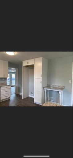 an empty kitchen with white cabinets and wood flooring in the background, is shown