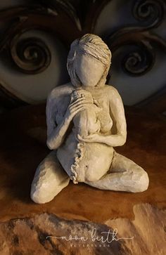 a white statue sitting on top of a wooden floor next to a stone headboard