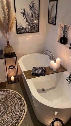 a white bath tub sitting in a bathroom next to a rug and two candles on top of it