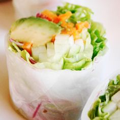 two rolls filled with lettuce, carrots and cucumber on top of a table