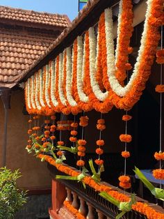 orange and white garlands hanging from the roof of a building with flowers on it