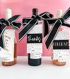 three wine bottles with black and white ribbons tied around them, each containing a thank you message