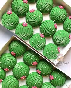 two boxes filled with green decorated cookies next to each other