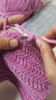 someone is knitting something with pink yarn