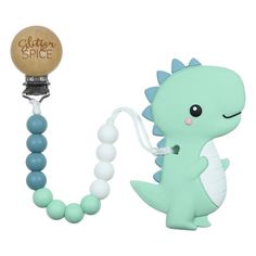 a pacifier with a green and white dragon on it's side, next to a wooden bead