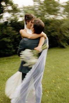 a bride and groom hugging each other in the grass