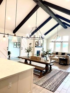 an open concept living room and dining area with vaulted ceilings, exposed beams, white walls, and wood flooring