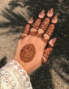 a woman's hand with henna tattoos on it and an intricate design in the middle