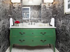 a bathroom with a green vanity and marble counter top next to a framed mirror on the wall