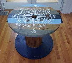 a wooden table with a compass painted on it's side sitting on a hard wood floor