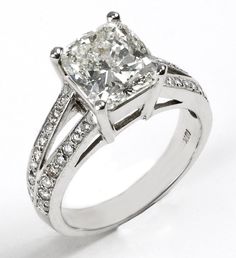 a white gold ring with a princess cut diamond in the center and pave set shoulders