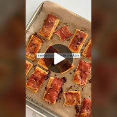 a pan filled with crackers covered in cheese and bacon on top of a baking sheet