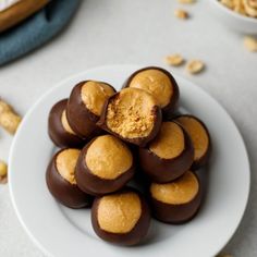 a white plate topped with chocolate covered peanut butter balls next to other bowls of nuts