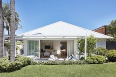 a white house with palm trees in the front yard and back door to the living room