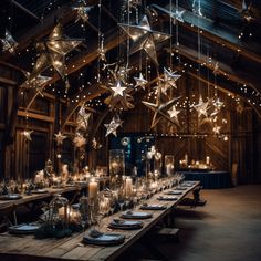 a wooden table topped with lots of candles and stars hanging from the ceiling above it