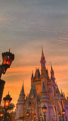 the castle is lit up at night in front of some street lamps and buildings with lights on them