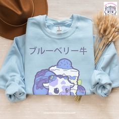 Introducing our adorable Kawaiicore Blueberry Cow sweatshirt! 🫐🐮 Featuring the lovable Bianca the Blueberry Cow surrounded by her favorite things: scrumptious blueberry cake and juicy blueberries! This delightful design is perfect for those who adore all things cute and whimsical. Crafted with your comfort in mind, this sweatshirt is a must-have for the colder months. It's made from a blend of 50% cotton and 50% polyester, ensuring a sturdy and warm garment that will keep you cozy when the tem Kawaii Cotton Streetwear Sweatshirt, Kawaii Cotton Sweatshirt For Streetwear, Harajuku Style Cotton Sweatshirt For School, Kawaii Cotton Sweatshirt For School, Kawaii Cute Crew Neck Tops, Cute Kawaii Crew Neck Top, Kawaii Crew Neck Top With Cute Design, Cotton Kawaii Sweatshirt For School, Blue Harajuku Cotton Sweatshirt