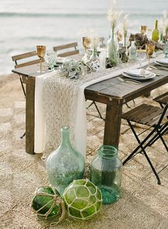 the table is set with green vases and plates