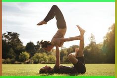 two people doing handstands on the grass with trees in the backgroud