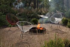 three chairs sitting around a fire pit in the middle of a field